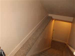 Stairway with dark carpet and a textured ceiling