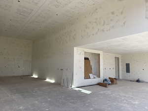 Empty room with electric panel and a towering ceiling