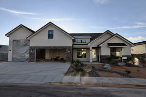 Modern farmhouse with driveway, stone siding, a garage, and stucco siding