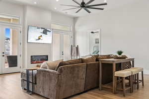 Living room with recessed lighting, a glass covered fireplace, ceiling fan, and wood finished floors
