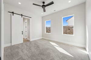 Unfurnished bedroom with carpet flooring, recessed lighting, visible vents, and a barn door