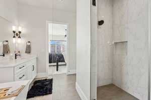 Ensuite bathroom featuring vanity, tile patterned floors, a marble finish shower, baseboards, and ensuite bathroom