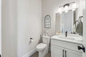 Bathroom with toilet, tile patterned floors, baseboards, and vanity