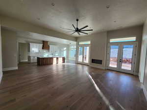 Unfurnished living room with french doors, dark hardwood / wood-style floors, and ceiling fan