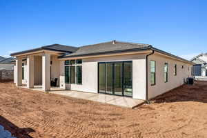 Back of house featuring a patio area, stucco siding, and a tiled roof