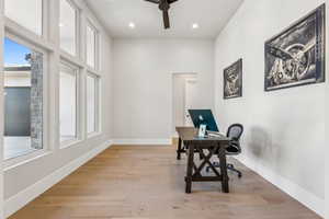 Home office featuring a ceiling fan, a healthy amount of sunlight, and light wood-style floors
