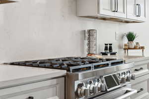 Room details with light countertops, white cabinets, and range