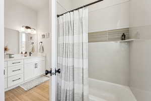 Full bath featuring vanity, wood finished floors, and shower / tub combo with curtain