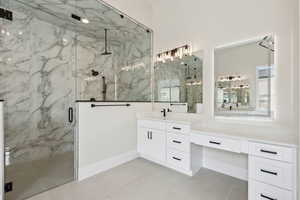 Full bathroom featuring tile patterned floors, a marble finish shower, and vanity