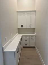 Interior space with light hardwood / wood-style floors, white cabinetry, and light stone countertops