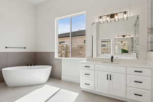 Bathroom with vanity, a shower with door, a freestanding tub, and a wainscoted wall