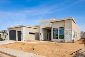 Contemporary home with concrete driveway, stone siding, and stucco siding