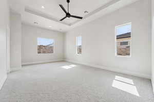 Empty room featuring a raised ceiling, carpet floors, a ceiling fan, recessed lighting, and visible vents