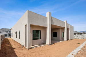 Rear view of house with a patio, fence, and stucco siding