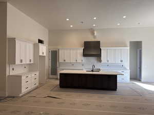 Kitchen with sink, premium range hood, tasteful backsplash, a towering ceiling, and a kitchen island with sink