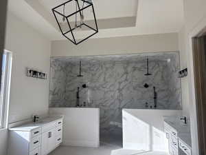 Bathroom with vanity, a chandelier, and tiled shower