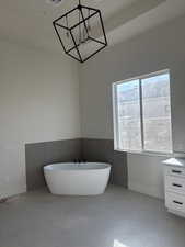 Bathroom with vanity, a notable chandelier, a bathing tub, and concrete floors