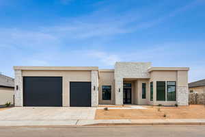 Contemporary house featuring an attached garage, stucco siding, stone siding, and concrete driveway