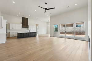 Unfurnished living room featuring light wood-style floors, a ceiling fan, recessed lighting, a towering ceiling, and visible vents
