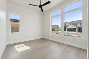Unfurnished room with ceiling fan, baseboards, plenty of natural light, and wood finished floors