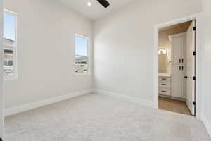 Unfurnished bedroom with baseboards, light carpet, and connected bathroom