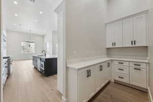 Kitchen with a sink, light countertops, a notable chandelier, recessed lighting, and light wood-style flooring