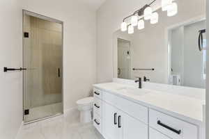 Full bathroom with a stall shower, vanity, baseboards, toilet, and marble finish floor