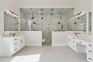 Full bath featuring a sink, a marble finish shower, and two vanities