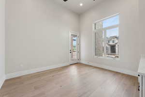 Unfurnished room featuring light wood-style floors, baseboards, ceiling fan, and a wealth of natural light