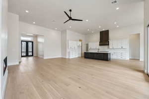 Unfurnished living room featuring ceiling fan, visible vents, baseboards, and light wood-style floors