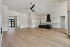 Unfurnished living room with visible vents, a towering ceiling, ceiling fan, recessed lighting, and light wood-type flooring