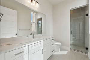 Bathroom featuring vanity, baseboards, a stall shower, and toilet