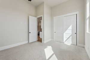 Unfurnished bedroom with light colored carpet and baseboards