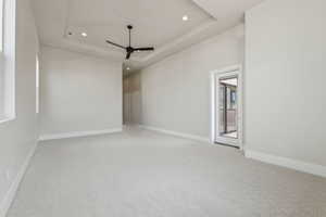 Carpeted spare room with baseboards, ceiling fan, a tray ceiling, and recessed lighting