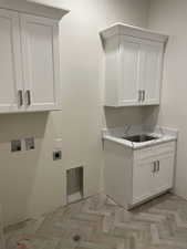 Laundry room featuring electric dryer hookup, sink, hookup for a washing machine, and cabinets