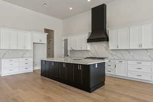 Kitchen with white cabinets, custom exhaust hood, a sink, and tasteful backsplash