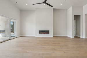 Unfurnished living room featuring recessed lighting, a ceiling fan, a glass covered fireplace, and light wood finished floors