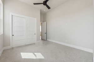 Unfurnished bedroom with light colored carpet, baseboards, vaulted ceiling, and a closet