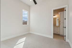 Unfurnished bedroom featuring a ceiling fan, baseboards, light carpet, and ensuite bath