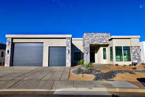 Contemporary home with stucco siding, stone siding, a garage, and driveway