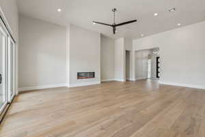 Unfurnished living room featuring visible vents, a glass covered fireplace, ceiling fan, recessed lighting, and light wood finished floors