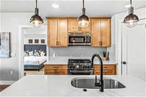 Kitchen with sink, tasteful backsplash, appliances with stainless steel finishes, and decorative light fixtures