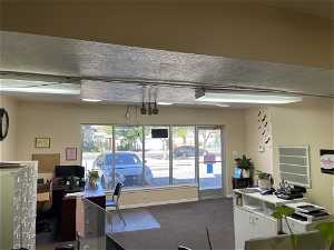 Carpeted office featuring a textured ceiling