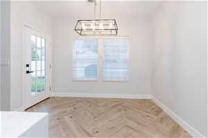 Unfurnished room featuring a notable chandelier and light parquet flooring