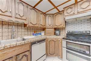 Kitchen with light tile floors, electric range oven, sink, tasteful backsplash, and white dishwasher