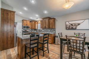 Kitchen featuring a kitchen island, appliances with stainless steel finishes, light hardwood / wood-style floors, and stone countertops