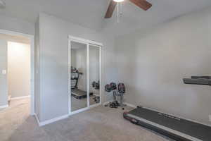 Workout room featuring ceiling fan and light colored carpet