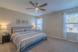 Carpeted bedroom featuring ceiling fan