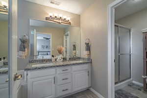 Bathroom with an enclosed shower, ceiling fan, tile floors, and dual bowl vanity