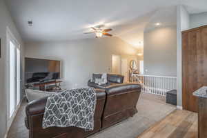 Carpeted living room featuring ceiling fan and lofted ceiling